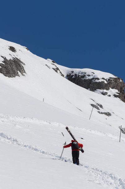 Patrulla de esquí que sube por una ladera montañosa con grandes esquís
 - Foto, Imagen