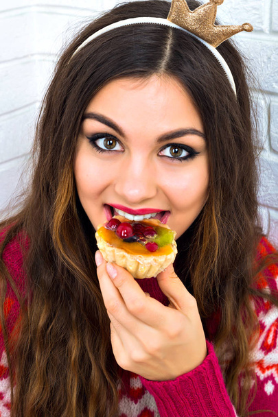 Young beautiful woman eating cake  in studio - Фото, зображення
