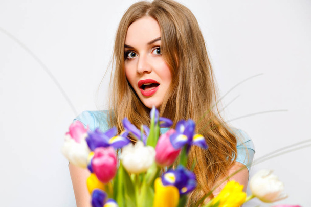 young surprised woman holding bunch of spring flowers  - Фото, зображення