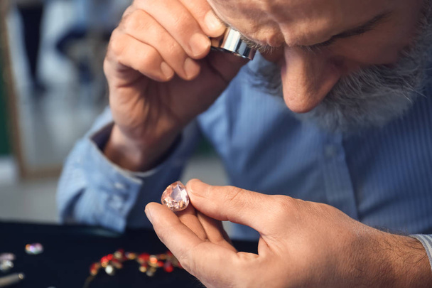 Jeweller examining gemstone in workshop, closeup - Photo, Image