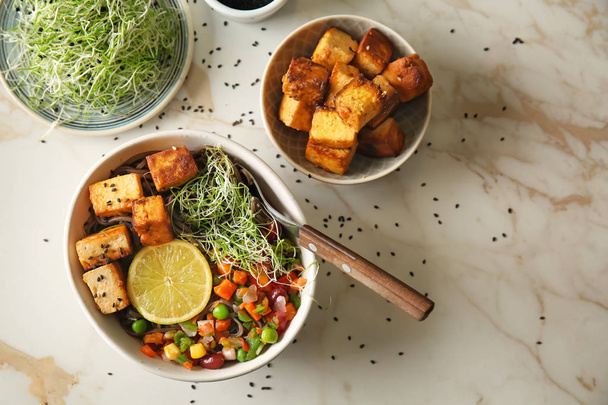 Kulhot maukasta paistettua tofu-juustoa ja vihanneksia pöydällä
 - Valokuva, kuva