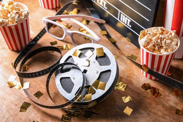 Film reel with popcorn and glasses on wooden table - Foto, immagini