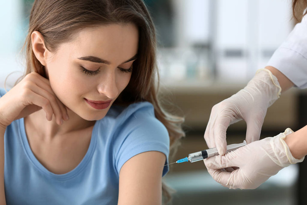Médico vacinando mulher contra a gripe na clínica
 - Foto, Imagem