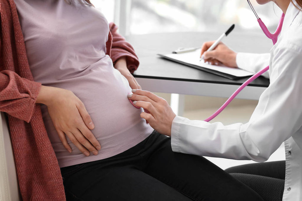 Nuori lääkäri tutkii raskaana olevan naisen klinikalla
 - Valokuva, kuva
