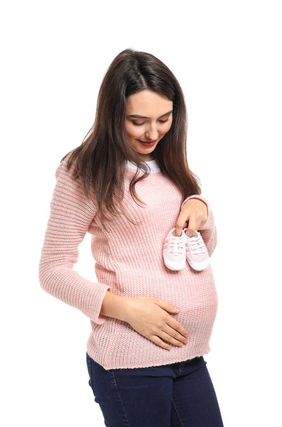 Portrait of beautiful pregnant woman with baby booties on white background - Foto, Imagen