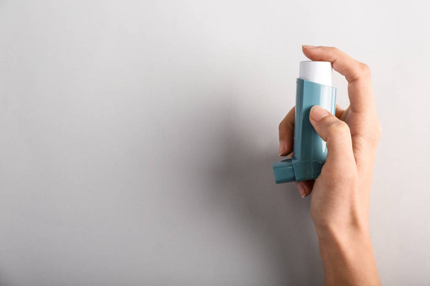 Female hand with inhaler against asthma on light background - Foto, Imagem