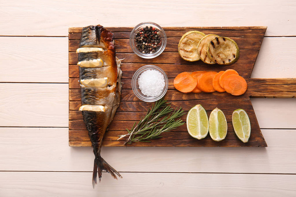 Board with tasty mackerel fish, vegetables and spices on wooden table - Photo, Image