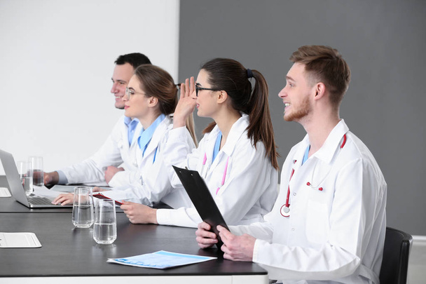 Молодые врачи сидят за столом во время встречи в клинике
 - Фото, изображение