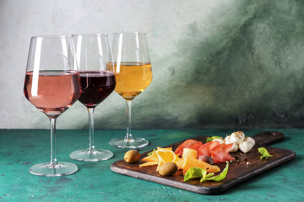 Glasses of different sorts of wine with snacks on color table - Photo, Image
