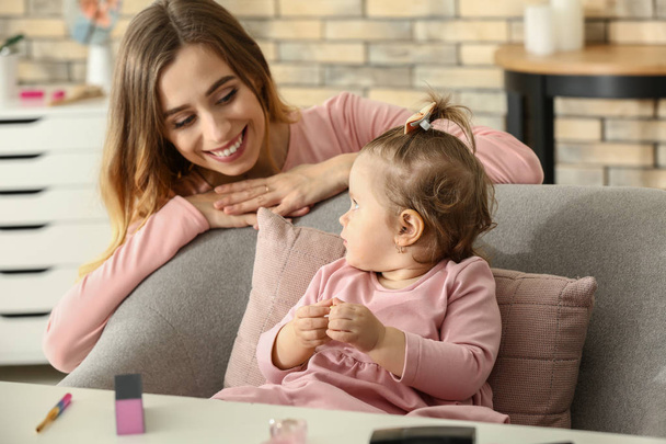 Young woman with her cute little daughter playing with cosmetics at home - Φωτογραφία, εικόνα