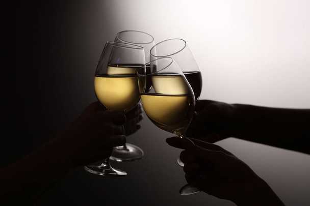 Women clinking glasses with tasty wine on dark background - Photo, Image