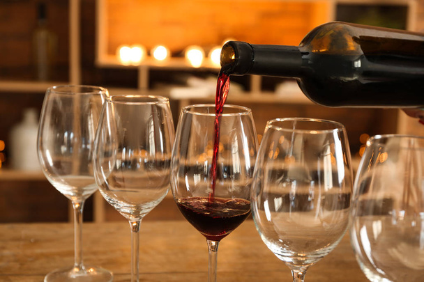 Наливание вкусного красного вина в бокалы на стол
 - Фото, изображение
