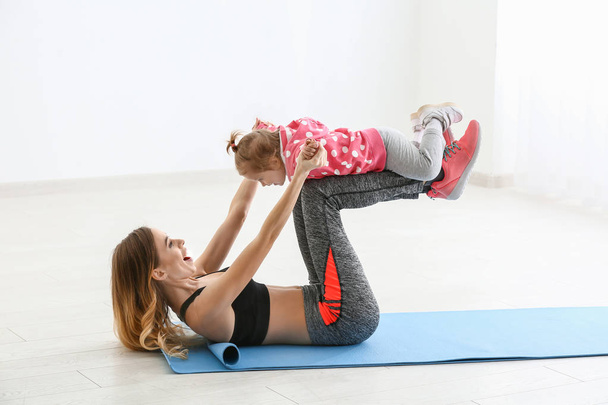 Young woman with her cute little daughter training indoors - Photo, Image
