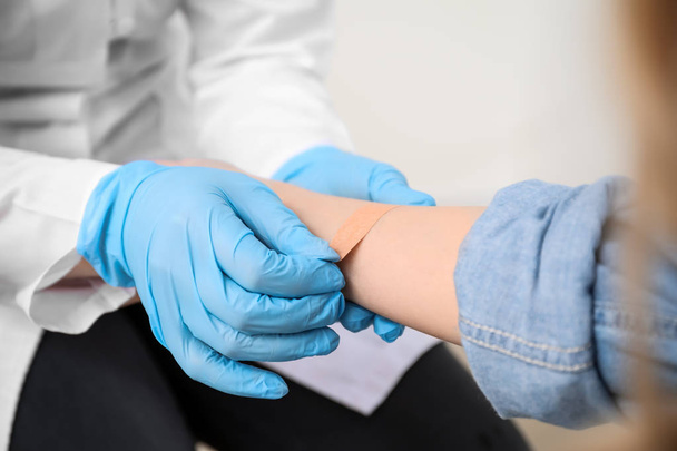 Doctor applying plaster onto hand of young woman, closeup - Valokuva, kuva
