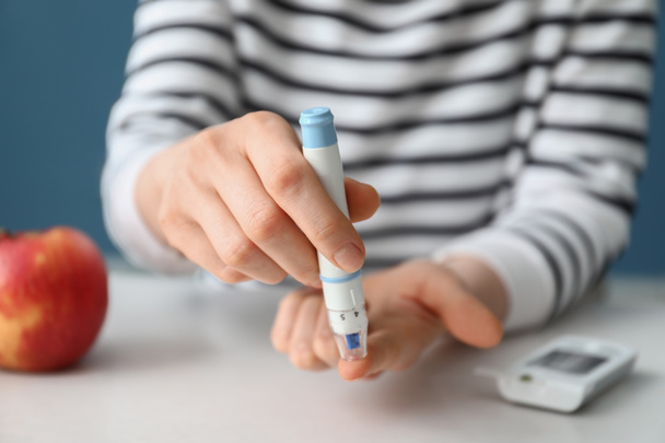 Диабетическая женщина берет образец крови с помощью ручки Ланцета дома, крупным планом
 - Фото, изображение