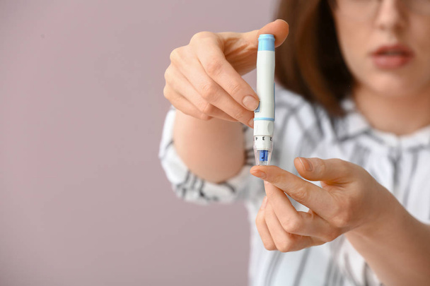 Diabetische vrouw bloedmonster nemen met lancet pen op de achtergrond kleur - Foto, afbeelding