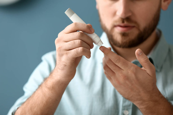 Diabetic man taking blood sample with lancet pen at home - Fotoğraf, Görsel