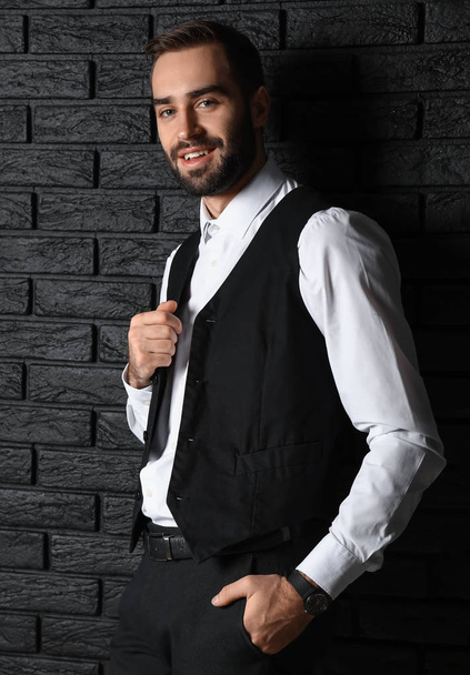 Handsome fashionable man near dark brick wall - Photo, Image