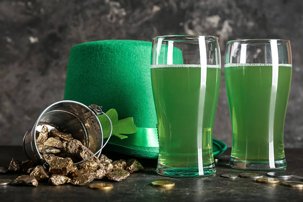 Composición con vasos de cerveza verde, sombrero de duende y pepitas de oro para el Día de San Patricio en la mesa
 - Foto, imagen