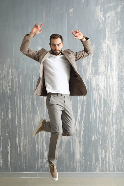 Bello uomo alla moda che salta contro il muro grunge
 - Foto, immagini