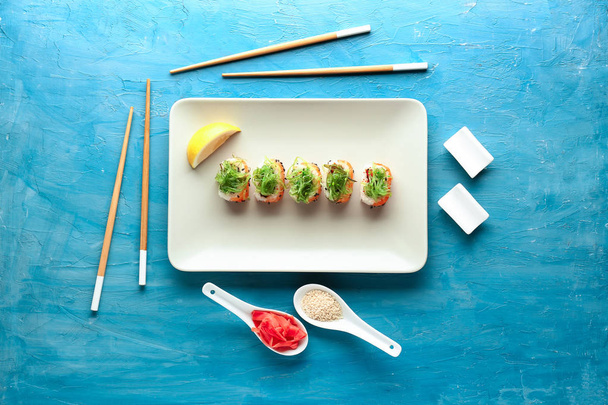 Plate with tasty sushi rolls on color table - Fotoğraf, Görsel