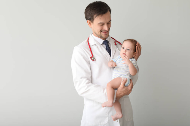 Pediatrician with cute little baby on white background - Fotó, kép
