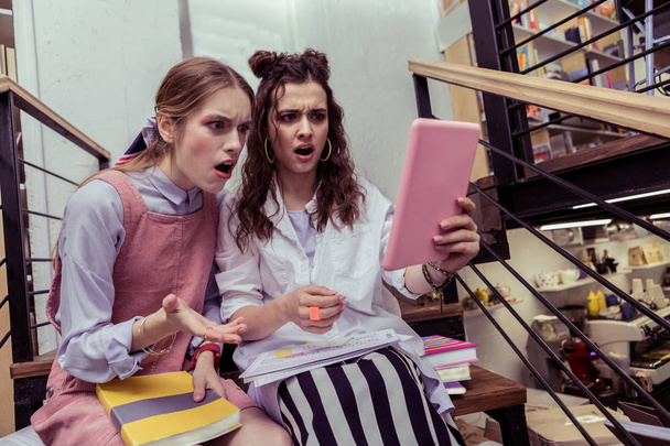 Шоковані експресивні дівчата дивляться на екран планшета з відкритими ротами
 - Фото, зображення