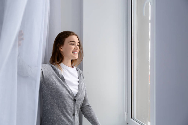 Young woman near window at home - Φωτογραφία, εικόνα