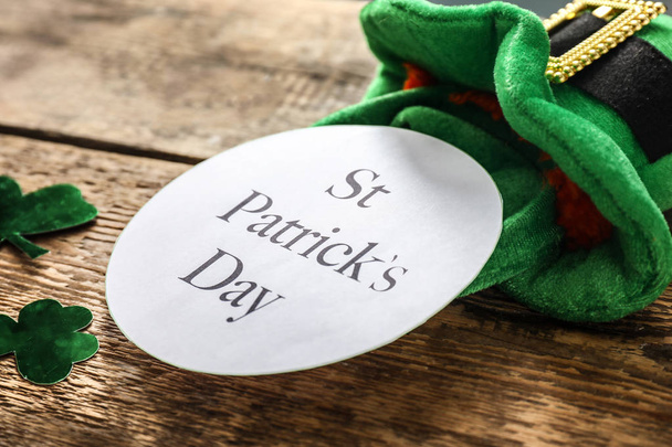 Karte mit dem Text "St. Patrick 's Day", grünem Hut und Kleeblatt auf Holzgrund - Foto, Bild