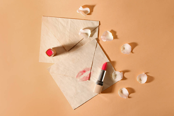 Rouge à lèvres, enveloppes et pétales de fleurs sur fond de couleur
 - Photo, image