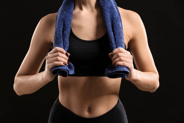 Sporty young woman with towel on dark background - Photo, Image