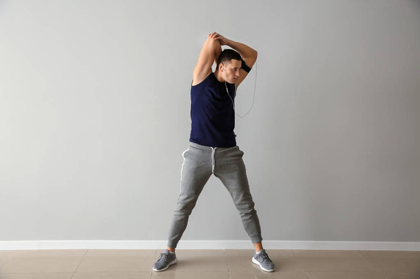 Sporty young man training against light wall - Photo, Image