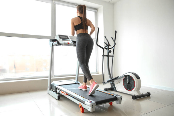 Sporty young woman on treadmill in gym - Photo, Image
