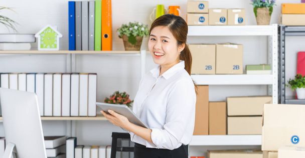 Молодая красивая, привлекательная азиатская деловая женщина с хвостиком пони, белая рубашка, черная юбка, держать планшет, выходное выражение при неожиданном заказе покупки от онлайн-клиентов, в стартап-офис фоне
 - Фото, изображение