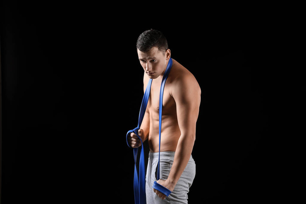 Sportowy młodego człowieka, trening z zespołem odporność na ciemnym tle - Zdjęcie, obraz