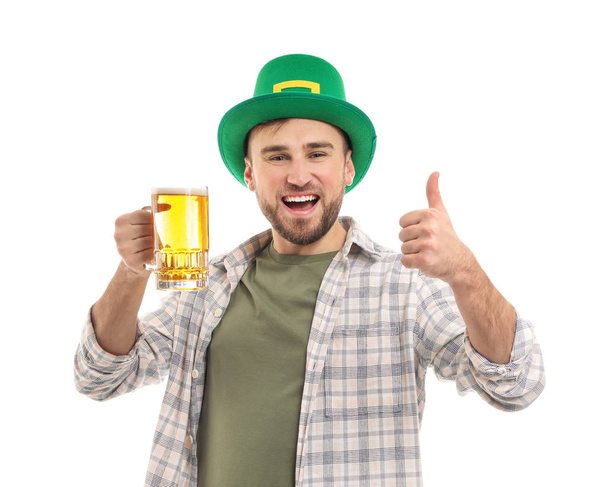 Beau jeune homme au chapeau vert et avec une tasse de bière montrant un geste de pouce sur fond blanc. Célébration de la Saint Patrick
 - Photo, image