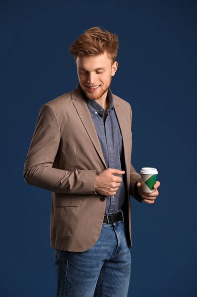 Fashionable young man with cup of coffee on color background - Foto, afbeelding