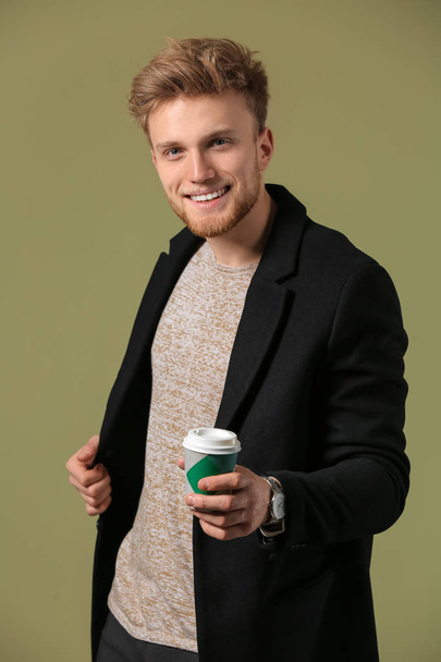 Модный молодой человек с чашкой кофе на цветном фоне
 - Фото, изображение