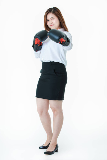 Half-length studio portrait of young, beautiful, attractive Asian lady, in white shirt and black skirt, with black leather boxing gloves, playfully mock fighting action, on isolated white background - Photo, Image