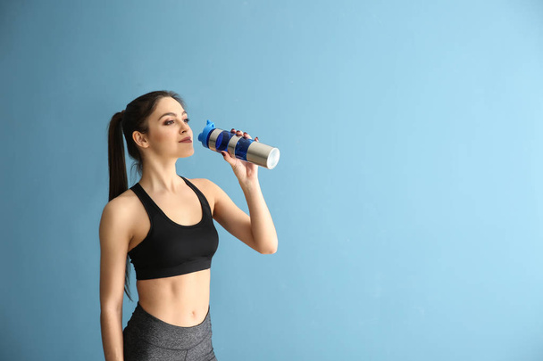 Sportliche junge Frau mit Flasche Wasser auf farbigem Hintergrund - Foto, Bild