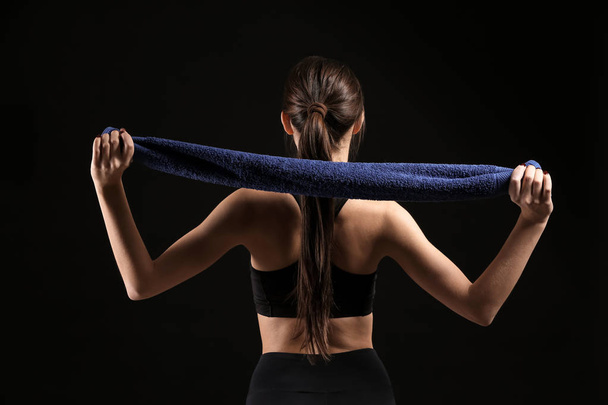 Mujer joven deportiva con toalla sobre fondo oscuro
 - Foto, Imagen