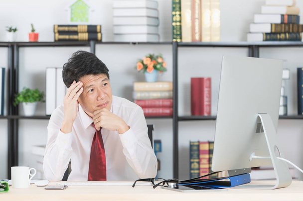 De meia-idade, Asiático, homem de negócios, em camisa branca, gravata vermelha escura, trabalhando em seu escritório de startup, sofrendo de dor de cabeça aguda, grimace, segurando a cabeça, com fundo de computador e escritório
 - Foto, Imagem