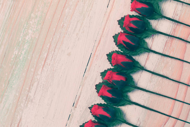 День Святого Валентина і любов концепція, облаштування красиві підроблені червоні троянди та листя, впорядкованої рядка на яскраві коричневий дерев'яними тлі, скопіювати простору на нижній стороні, стиль квартира мирян, top подання Вітальна листівка - Фото, зображення