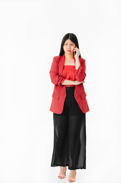 Volledige lengte studio portret van jonge aantrekkelijke Aziatische vrouw, lange zwarte haren, bril, in casual mode praten aan de telefoon met een stressvolle gebaar, op zichzelf staande witte achtergrond - Foto, afbeelding