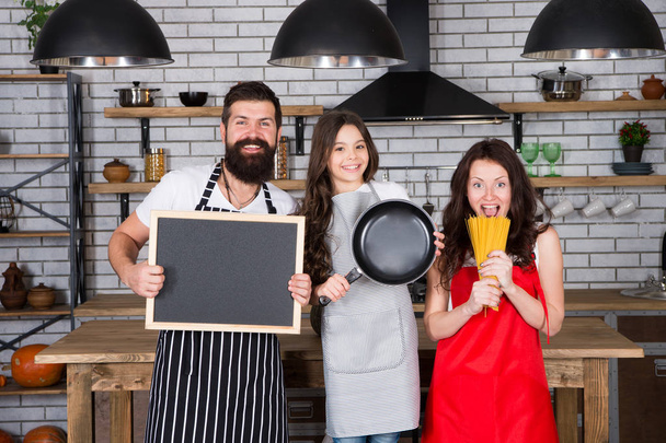 Father, mother and child cooking. Mother father with little girl. Family day. Happy family in kitchen. Little girl with parents in apron. Bearded man with board, copy space. Cooking with passion - 写真・画像