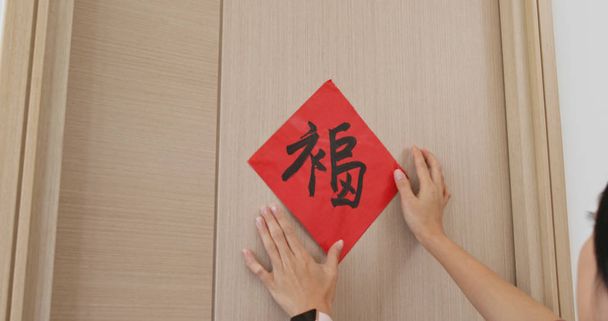 Frau klebt rote Kalligraphie auf die Tür, die zu Hause das chinesische Neujahrswort ziert, bedeutet Glück - Foto, Bild