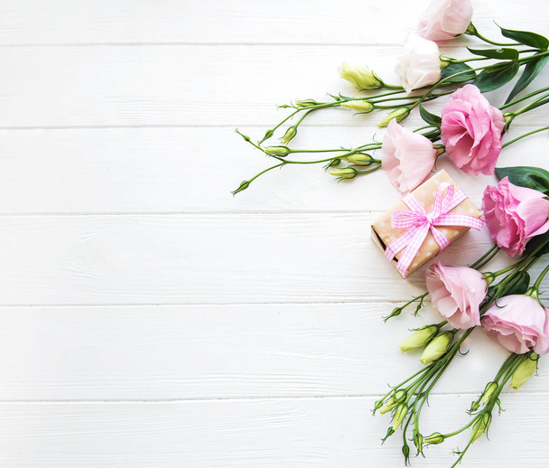 Taze pembe eustoma çiçek ve hediye kutusu ahşap arka plan üzerinde - Fotoğraf, Görsel