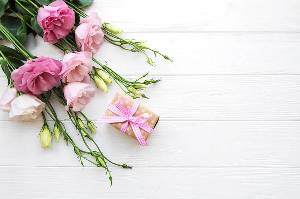 Fresh pink eustoma flowers and gift box on wooden background - Photo, Image