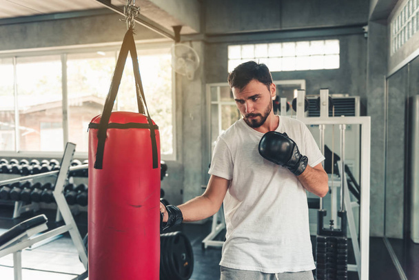 Sportowy bokser jest wbicie ćwiczenia w Fitness Gym., portret człowieka boks jest praktykowanie pracy nóg w sprawny i rękawice bokserskie., przystojny mężczyzna jest robienie ćwiczeń wykrawania z treningowe torby. - Zdjęcie, obraz