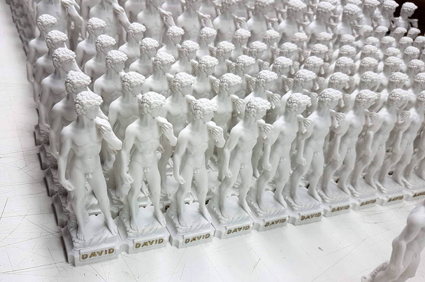 στράτευμα από αγάλματα του Δαβίδ του Μιχαήλ Αγγέλου, γλυπτά σε μάρμαρο ή το ασβεστοκονίαμα έτοιμο να αγοράζονται από τους τουρίστες - Φωτογραφία, εικόνα